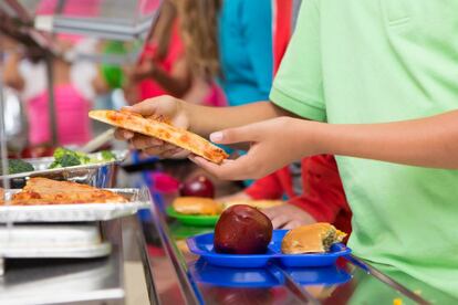 un niño elige pizza en el comedor escolar.