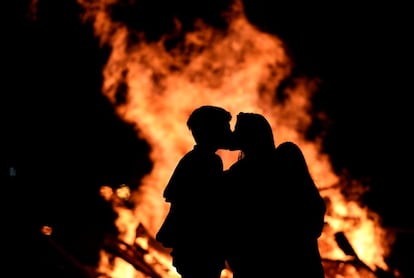 Una pareja se besa junto al fuego mientras celebran la noche de San Juan en la playa de Poniente en Gijón (España), el 24 de junio de 2017.