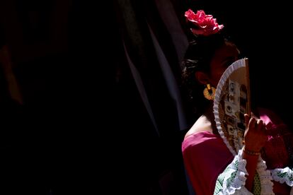 Una joven vestida de flamenca se abanica para refrescarse y se protege del sol en la puerta de su caseta. La temperatura en Sevilla ha superado los 35 grados centígrados este martes.
