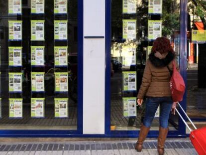 Anuncios de viviendas en venta en el escaparate de una inmobiliaria en Madrid.