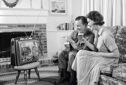 Una pareja mira su televisión portátil en una fotografía tomada en los años sesenta.