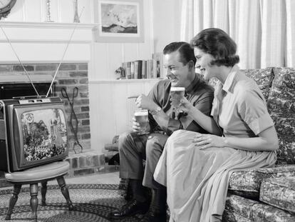 Una pareja mira su televisión portátil en una fotografía tomada en los años sesenta.