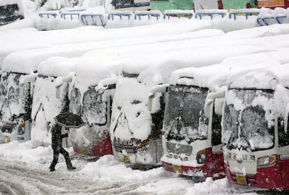 Un hombre pasa junto a unos autobuses cubierto de nieve en Gangneung (Corea del Sur).