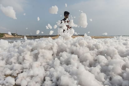 Un hombre camina sobre espuma causada por agentes contaminantes, en una playa de Chennai (India).