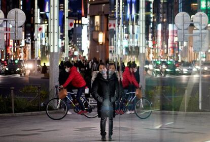 Los transeúntes se reflejan en un escaparate en el distrito comercial de Ginza en Tokio, Japón, este martes. El Gobierno Metropolitano de Tokio anunció que ha confirmado 1.591 casos de coronavirus en las últimas 24 horas, una nueva cifra récord.