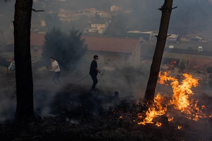 Residentes intentan apagar las llamas que se acercan a sus viviendas en Covelo, este martes. 
