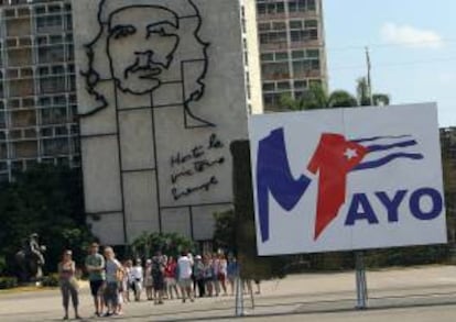 Turistas caminan Plaza de la Revolución de La Habana (Cuba), junto a uno de los carteles colocados para el desfile que se celebrará mañana por el Día Internacional de los Trabajadores.