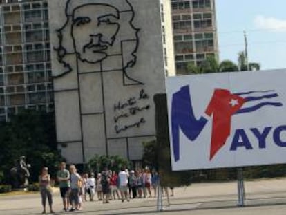 Turistas caminan Plaza de la Revolución de La Habana (Cuba), junto a uno de los carteles colocados para el desfile que se celebrará mañana por el Día Internacional de los Trabajadores.