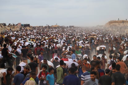 Un grupo de palestinos cargan sacos con comida y suministros que están entrando en Gaza en camiones desde Israel, en Beit Lahia, al norte de la Franja, este martes. 