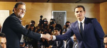El jefe del Gobierno, Mariano Rajoy,iz., y el líder de Ciudadanos, Albert Rivera, se estrechan la mano durante la reunión de sus respectivas delegaciones en la que van a certificar el acuerdo de investidura.l