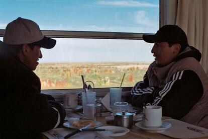 Cerca de Challapata, dos bolivianos conversan en el vagón restaurante del Wara Wara del Sur, uno de los trenes que atraviesa el altiplano, con campos de quinua al fondo.