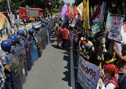 Policías antidisturbios bloquean el paso a un grupo de indígenas filipino que se manifiesta contra la actividad minera frente al hotel que acogerá durante los próximos tres días una conferencia anual sobre minería, en Manila (Filipinas).