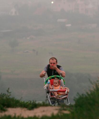 Un hombre se cubre la boca con un pañuelo mientras empuja el carrito de su hija a unos 30 kilómetros de Moscú.
