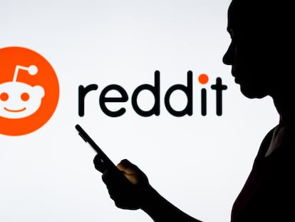 Una mujer sostiene un teléfono inteligente con el logotipo de Reddit en el fondo.