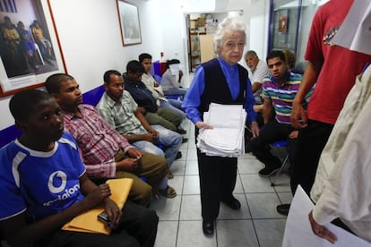 Un m&eacute;dico griego pasa entre pacientes que esperan en una consulta en Atenas. 