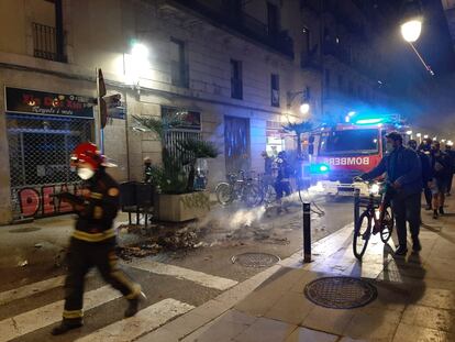 Los bomberos intervienen para apagar las llamas de los contenedores incendiados en la calle Princesa