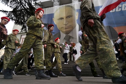 Youth take part in an action to mark the ninth anniversary of the Crimea annexation from Ukraine next to an image of Russian President Vladimir Putin in Yalta, Crimea, on March 17, 2023.