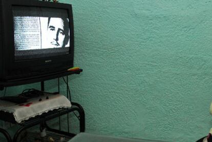 Una mujer sigue por televisión la serie <i>El que debe vivir</i>, en La Habana.