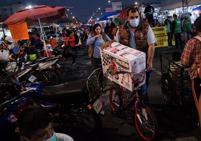 Un hombre carga una bicicleta y juguetes en un tianguis en el centro de Ciudad de México, un día antes del Día de Reyes.