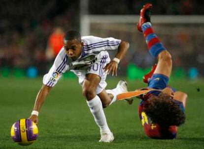 Puyol cae al césped mientras Robinho intenta proseguir la jugada.