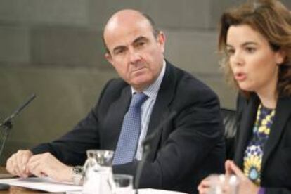 El ministro de Economía, Luis de Guindos, y la vicepresidenta del Gobierno, Soraya Sáenz de Santamaría, durante la rueda de prensa que ofrecieron ayer al término de la reunión del Consejo de Ministros, en el Palacio de la Moncloa.