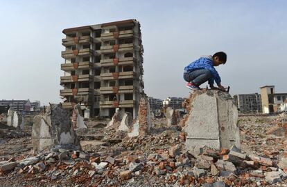 Um menino brinca em uma parede derrubada diante de um edifício parcialmente demolido em Hefei, província de Anhui, em 22 de abril de 2015. Mais de uma dúzia de famílias tem vivido nessas condições há mais de dois anos por não chegarem a um acordo de compensação.