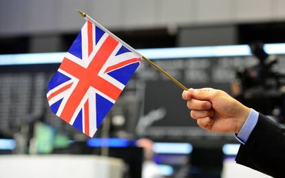 Un reportero de televisión sostiene una bandera británica en la Bolsa de Frankfurt.