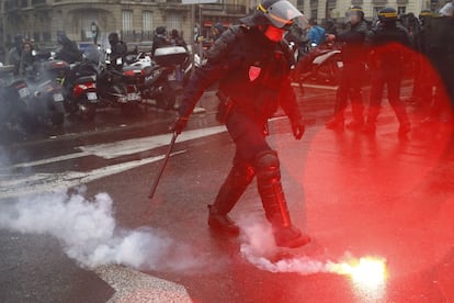 Un policía francés junto a una bengala lanzada, durante la manifestación contra la reforma laboral por las calles de París (Francia), el 31 de marzo de 2016.