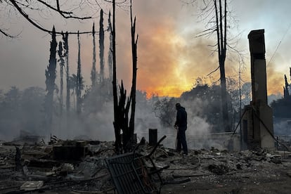 Un residente sofoca con una manguera los puntos calientes de una propiedad devastada por el fuego en el vecindario de Pacific Palisades de Los ?ngeles, el mircoles.