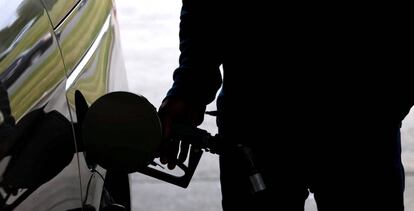 Una hombre llena el depósito de combustible. 