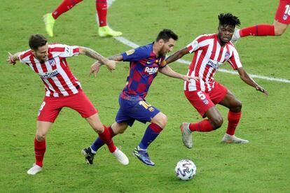 El delantero argentino del FC Barcelona Lionel Messi se lleva la pelota ante los jugadores del Atlético de Madrid Saúl Ñíguez (a la izquierda) y Thomas Partey.