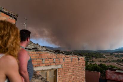 Dos vecinos observan el humo del incendio al fondo en Sant Martí de Tous, Barcelona. Este incendio permanece activo desde que comenzó el sábado por la tarde en Santa Coloma de Queralt (Tarragona).