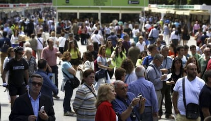 Lectores en el Parque del Retiro en busca del libro que comprar&aacute;n durante la Feria del Libro de Madrid.