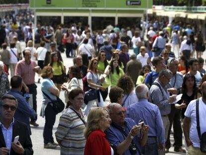 Lectores en el Parque del Retiro en busca del libro que comprarán durante la Feria del Libro de Madrid.