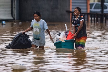 Unas mujeres caminan por una calle inundada intentando salvar sus pertenencias en Acapulco, Guerrero.