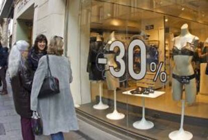 Varias mujeres conversan frente a un escaparate de una tienda con precios rebajados. EFE/Archivo