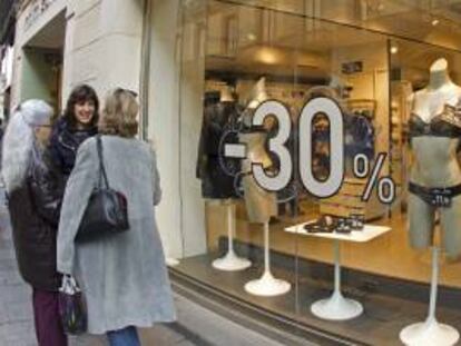 Varias mujeres conversan frente a un escaparate de una tienda con precios rebajados. EFE/Archivo