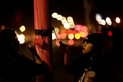 Varios activistas pintan una cruz negra sobre un fondo rosado en un poste de luz para recordar a las mujeres que han desaparecido o fueron asesinadas, en Ciudad Juárez, México.