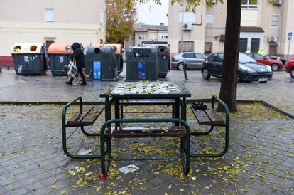 Una de las mesas de la plaza en la que falleció William y los contenedores junto a los que estaba el chico.