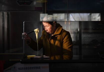 Una mujer prepara un tazón de fideos en un restaurante en Pekín (China).