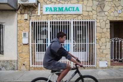 Un chaval en bicicleta pasa por delante de la farmacia de Balsa de Ves, cerrada permanentemente. 
