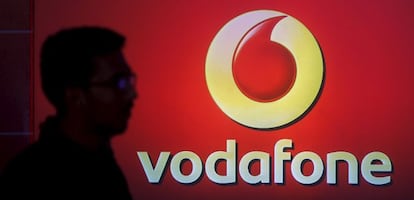 Un hombre se pasea por delante de un logo de Vodafone.