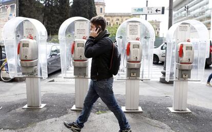 Un peat&oacute;n, junto a unas cabinas de Telecom Italia en Roma.