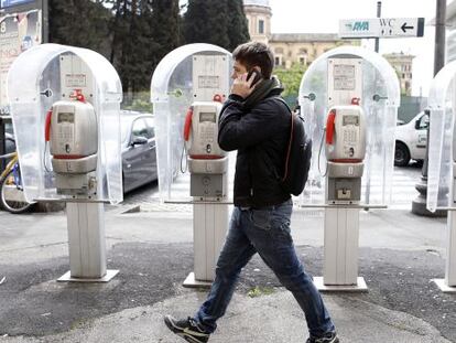 Un peat&oacute;n, junto a unas cabinas de Telecom Italia en Roma.