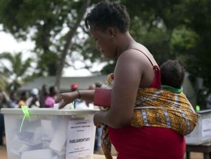 Una mujer vota con su hijo a la espalda durante las elecciones de Ghana en 2012.