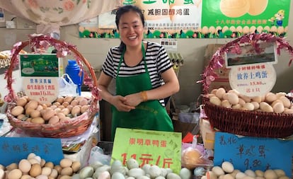 Vendedora de huevos sonríe risueña en su puesto del mercado.