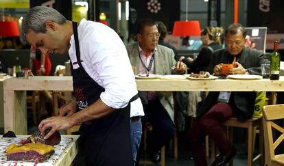 Un cocinero prepara un plato en un expositor de Alimentaria.