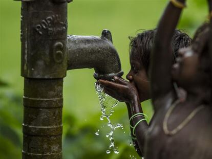 Unos niños beben agua de un pozo en Madhubani, en la región india de Bihar.