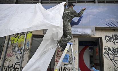 Un trabajador cubre las ventanas de un banco antes del paro nacional en Colombia.