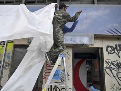 Un trabajador cubre las ventanas de un banco antes del paro nacional en Colombia.
